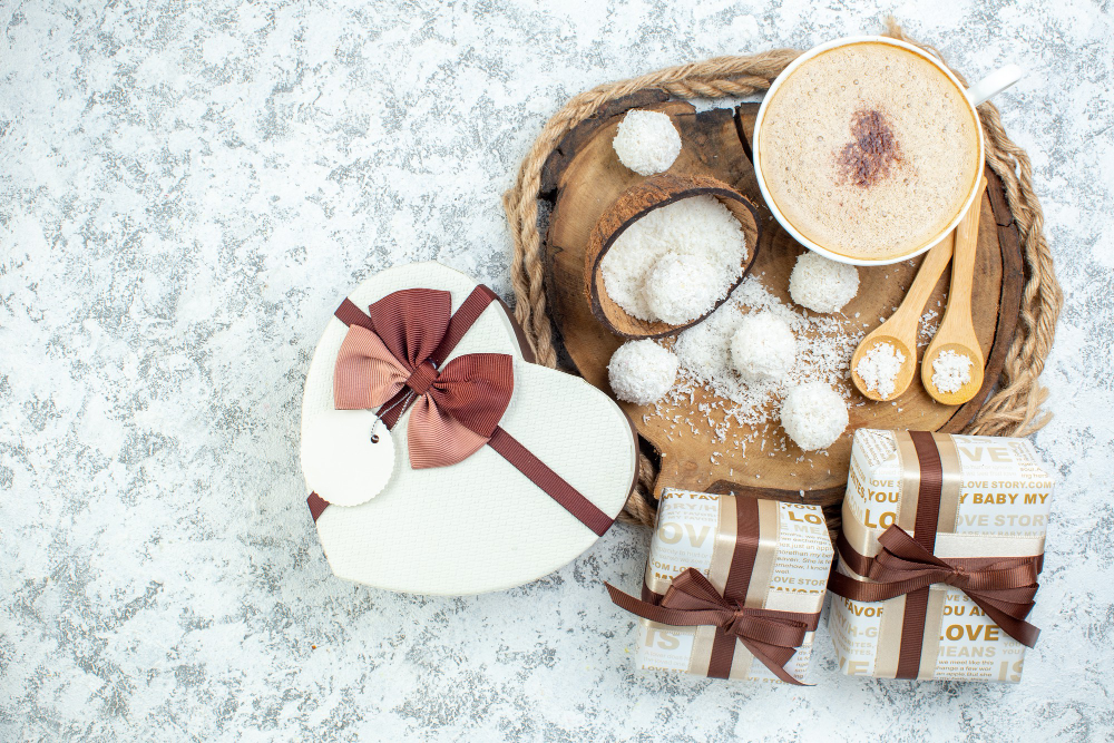 vista-superior-taza-capuchino-tazon-polvo-coco-cucharas-madera-sobre-tablero-madera-regalos-caja-regalo-forma-corazon-sobre-superficie-gris